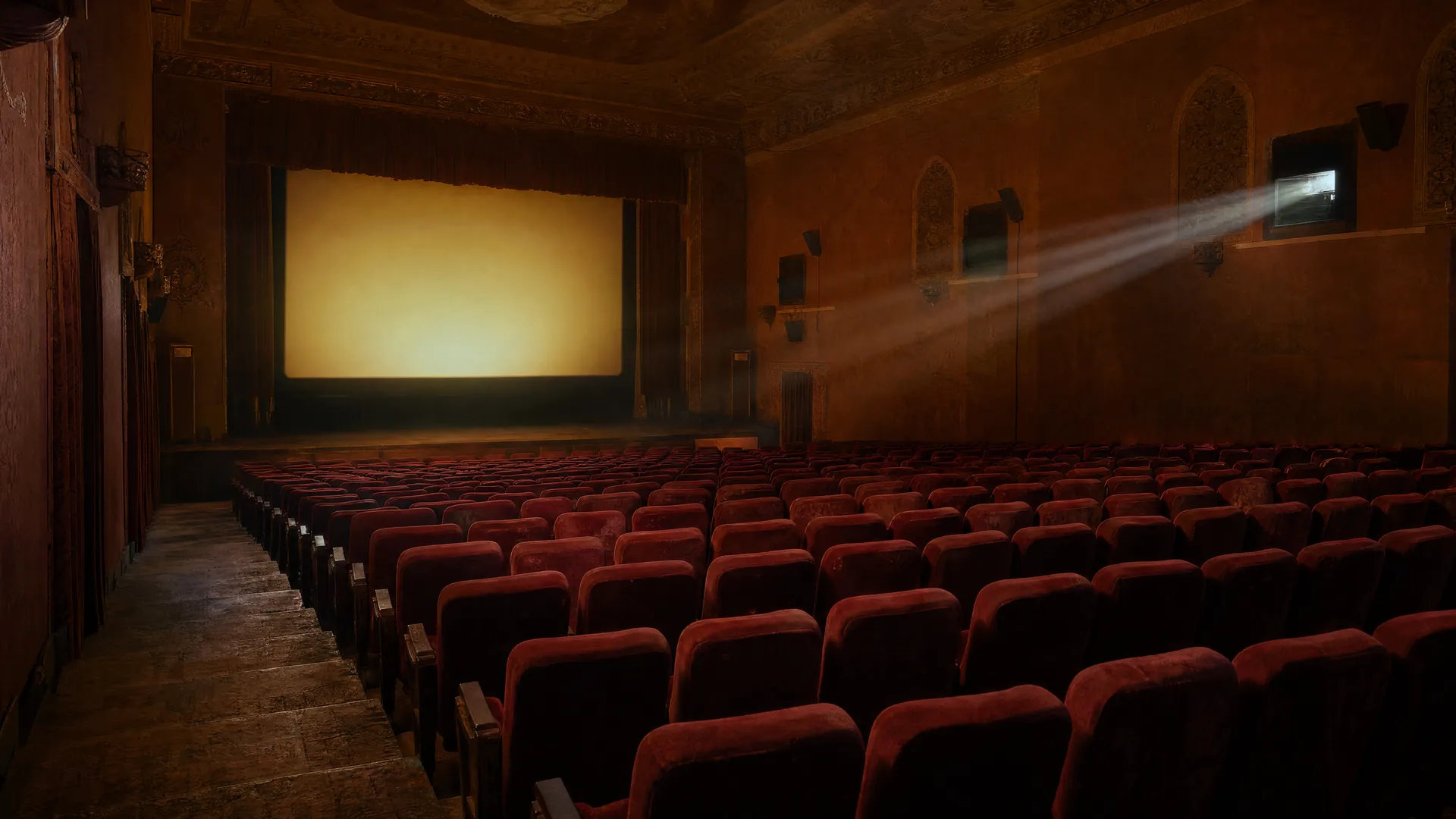 Empty vintage cinema hall with red velvet seats facing a glowing blank screen, a projector beam cutting through dusty amber light.